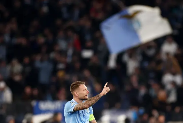 Immobile points to the stands as fans wave flag behind him.