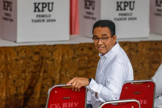 Indonesian Presidential candidate Anies Baswedan sat on a chair looking over his shoulder.