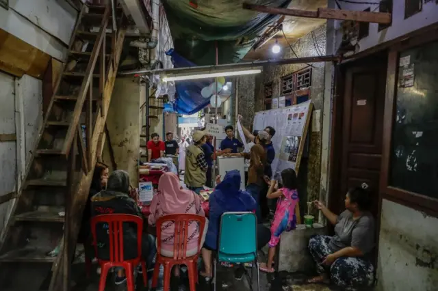 An election official holds a ballot during vote counting at a slum area in Jakarta