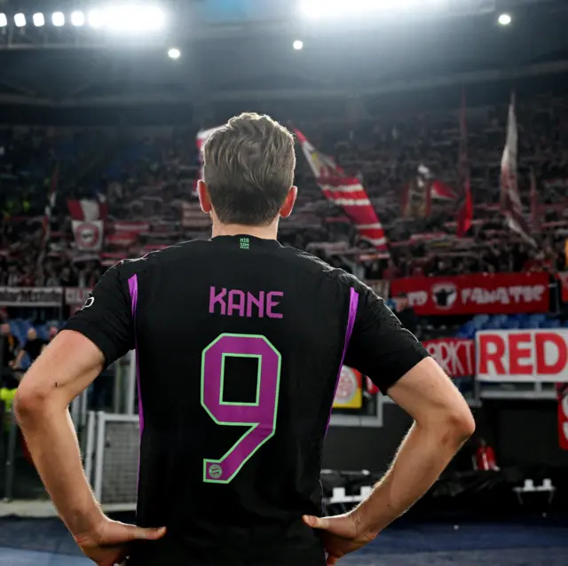 Kane stands in front of the travelling fans with his hands on his hips.