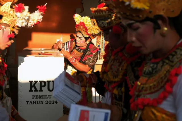 Electoral officers dressed in Balinese opera costumes prepare ballot boxes before polls opened