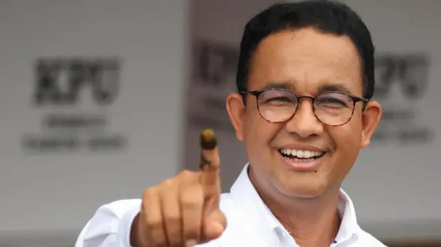 Presidential candidate Anies Baswedan shows his ink-stained finger after casting his vote at a polling station during the general election in Jakarta, Indonesia, February 14, 2024.