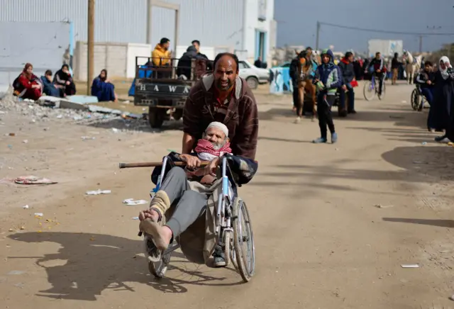 A man pushing a man in a wheelchair