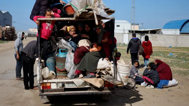 Displaced civilians on the back of a car with supplies