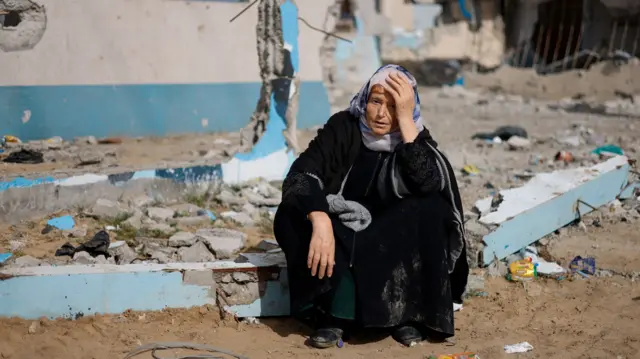 A displaced woman sitting in rubble