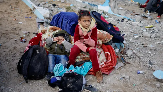 Children rest outside, as Palestinian arrive in Rafah after they were evacuated from Nasser hospital