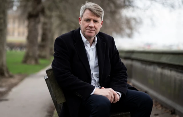 Chris Skidmore sits on a bench near Parliament