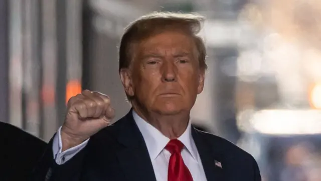 Trump raises his fist and looks at the camera