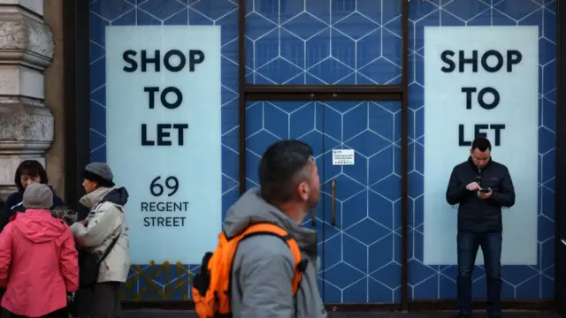 Shoppers walk by an empty shop, with a to let sign