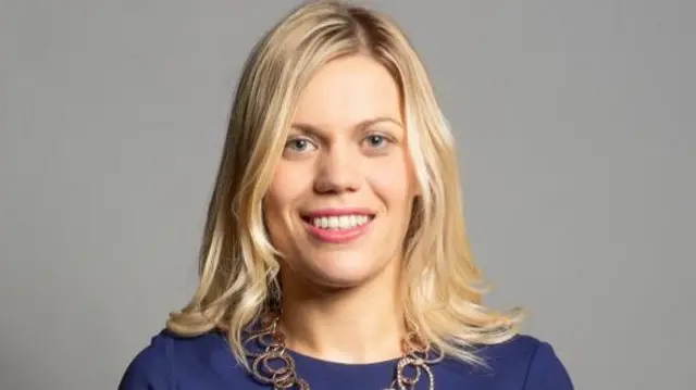 Miriam Cates MP standing in a blue dress for her official portrait in 2019