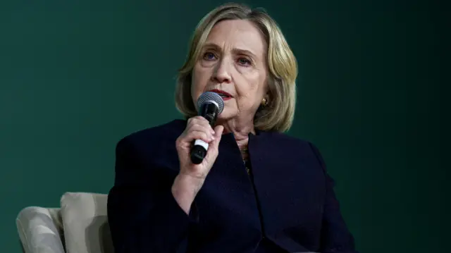 A seated Hillary Clinton speaking into a microphone at COP28 in Dubai in December 2023