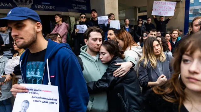 Russian citizens protest and hold signs in front of the Russian embassy in Lisbon