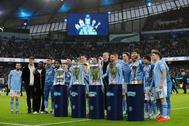 Manchester City players pose for a photograph with five trophies