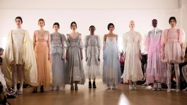 A row of models present dressed in flowy dresses with puffy sleeves present creations at the Bora Aksu during London Fashion Week