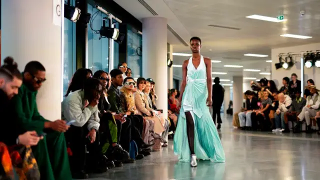 A model walks the catwalk at London Fashion Week in a flowy blue dress