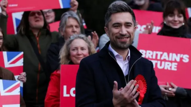 Labour MP Damien Egan standing in front of Labour campaigners with signs