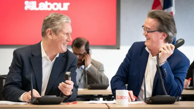 Labour leader Sir Keir Starmer sits with musician Feargal Sharkey while phone canvassing in the Wellingborough and Kingswood by-elections.