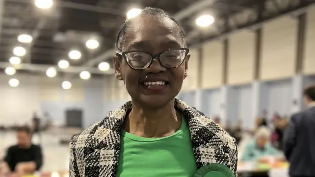 Kingswood Green Party candidate Lorraine Francis. She is seen stood in a sports hall and is smiling into the camera.