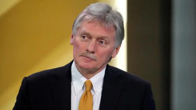 Dmitry Peskov wearing a suit with a yellow tie