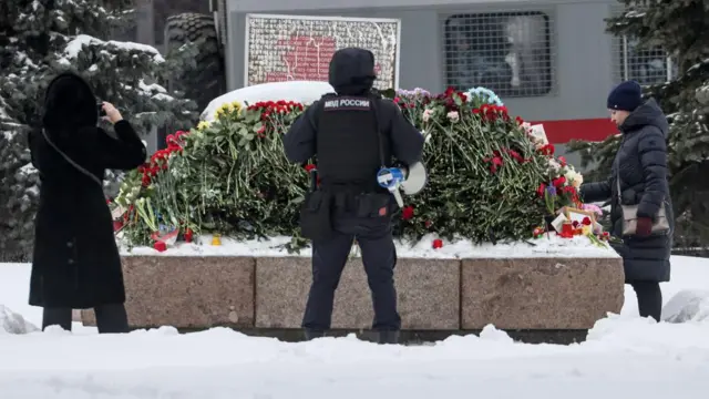 People lay flowers mourning Russian opposition leader Alexei Navalny's death near the memorial to political prisoners in Moscow