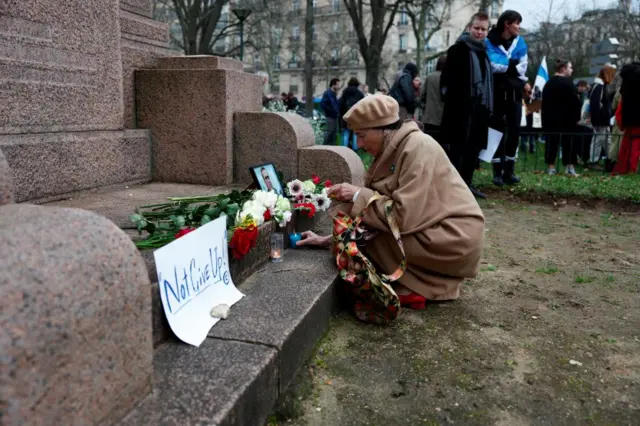 A woman places a candle next to a portrait of Russian opposition leader Alexei Navalny following Navalny's death as people gather near the Russian embassy, in Paris, France