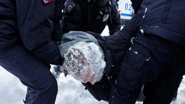 Police officers detain a man at a gathering remembering Navalny in Moscow