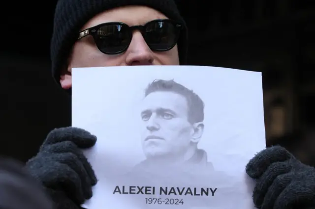 Man holds up picture of Alexei Navalny at a vigil outside the Russian consulate in New York City,