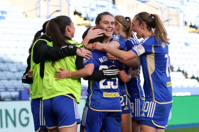 Momiki is mobbed by teammates after scoring.