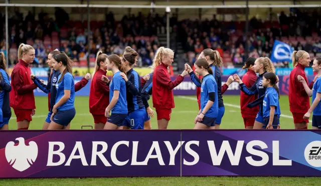 Players shake hands on the pitch before kick off.