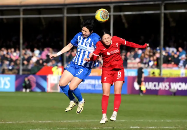 Geum-min and Nagano compete in an aerial duel for the ball.