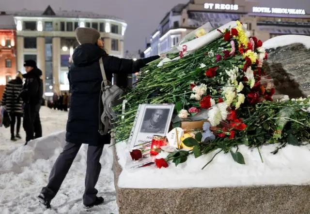 A woman lays flowers at the monument to the victims of political repressions following the death of Russian opposition leader Alexei Navalny, in Moscow, Russia February 16, 2024.