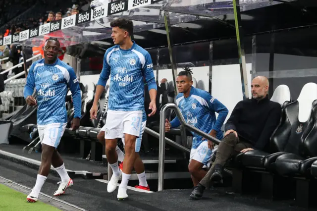 Jeremy Doku and Matheus Nunes emerge from the tunnel, watched by Manchester City boss Pep Guardiola