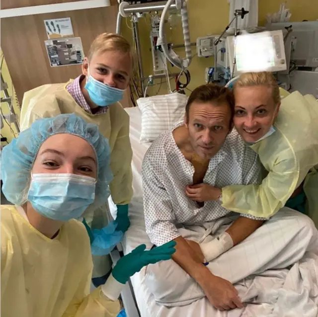 Navalny and his wife Yulia pose with nurses as he lays in bed in hospital