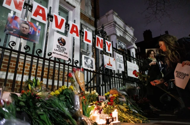 People leave flowers as they gather to mourn late Russian opposition leader Alexei Navalny outside the Russian Embassy in London