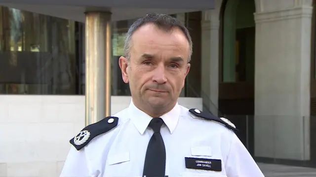 Cdr Savell in front of camera in his uniform