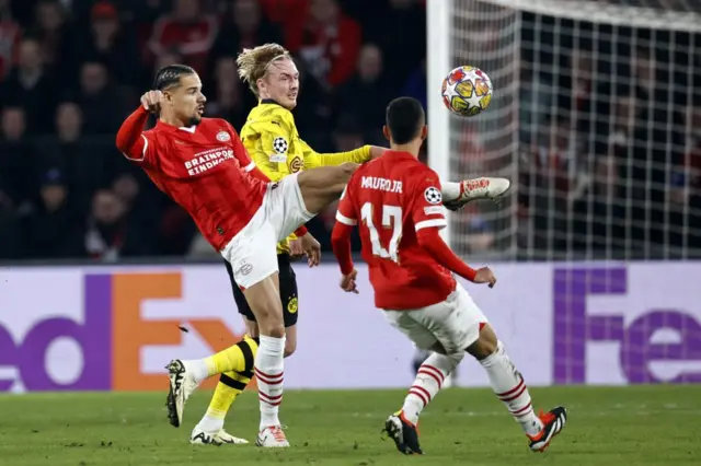 Players of PSV and Dortmund scramble for the ball in midfield.