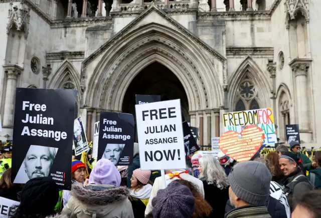 Protesters stand outside the high court with placards that read "Free Julian Assange"