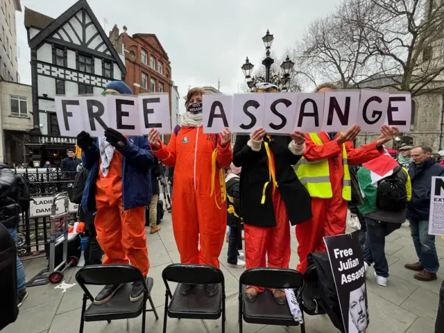 Supporters of Julian Assange stand on chairs and spell out 'Free Assange'