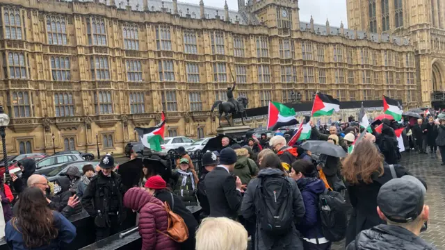 Protesters are flying Palestinian flags and singing as they wait outside parliament