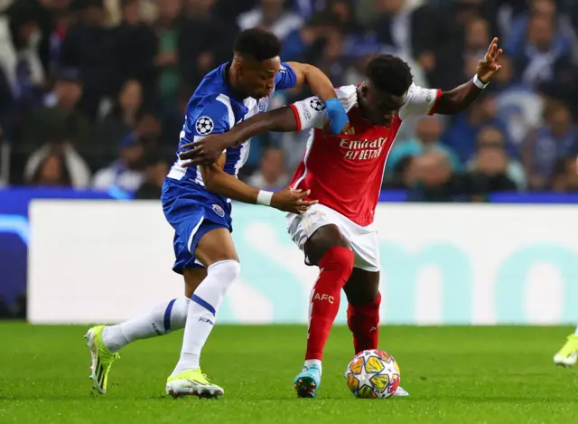 Saka holds off a challenge from behind in midfield.