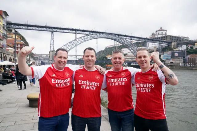 Arsenal fans stand on the riverside in Porto.