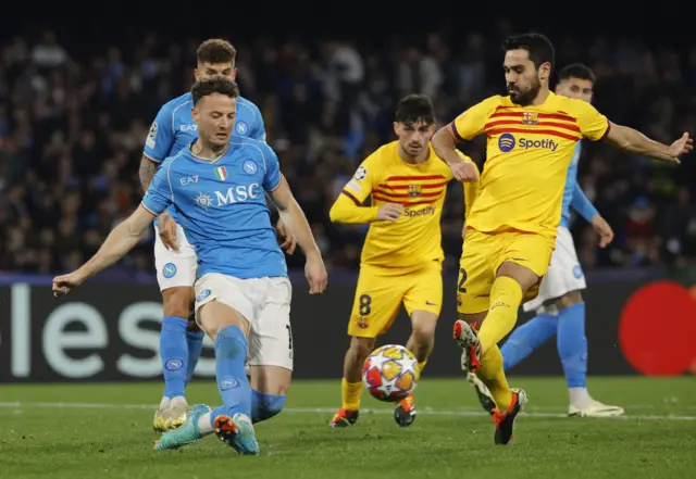 Gundogan shoots at goal for Barcelona as Napoli defenders try to block.