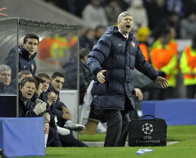 Arsene Wenger stands in front of the Dragao dugout as his staff watch on.