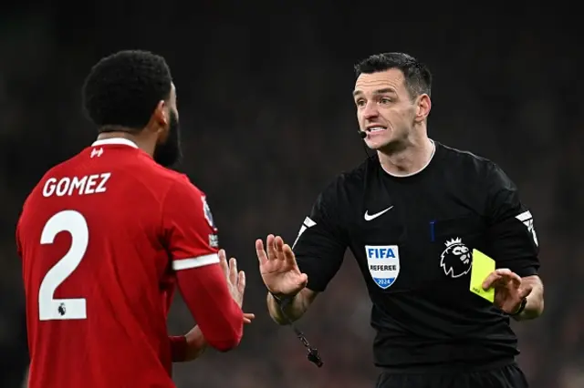 Andrew Madley gives a yellow card to Liverpool's English defender #02 Joe Gomez