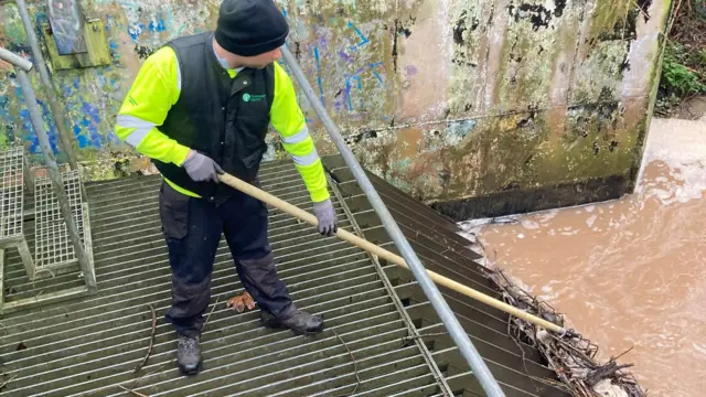 Environment Agency worker clears a debris screen