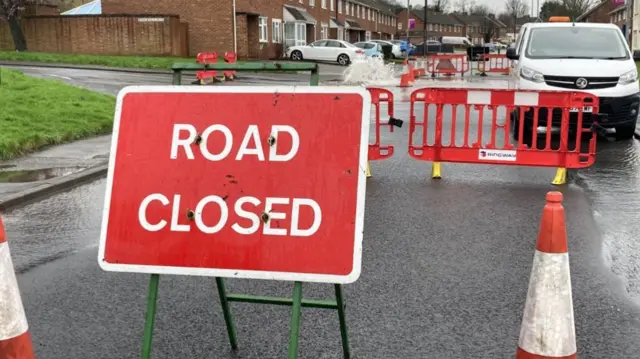 A road closed sign and a burst water-main