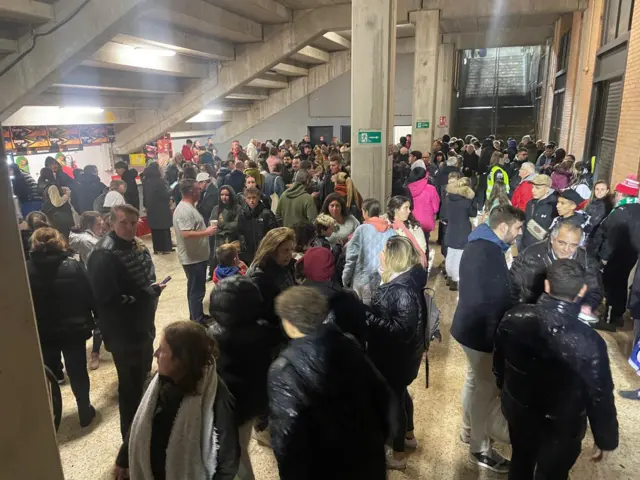 Fans take shelter underneath the stands as the rain pours down.