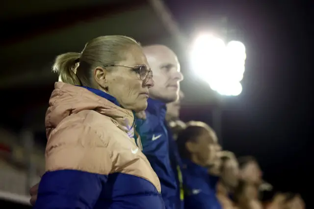 Wiegman stands alongside her staff in front of the dugout.