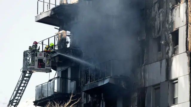 Firefighters cool off the multistorey residential block ravaged yesterday by a huge fire that killed at least four people, in Valencia on February 23, 2024