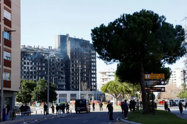 People stand at the scene of a fire in an apartment building in Valencia, Spain, February 23, 2024